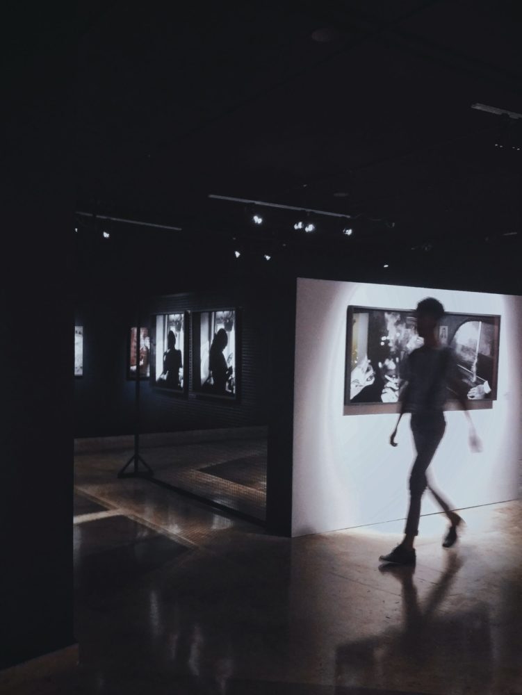 a silhouetted person walking through a gallery of photos