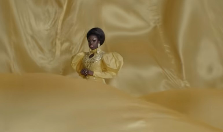 Bob the Drag Queen in a yellow gown on a billowing yellow background