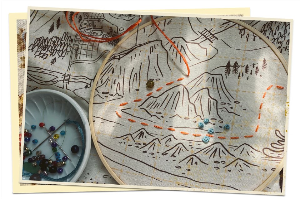 a hand drawn map, on fabric, with some colored lines of embroidery in it