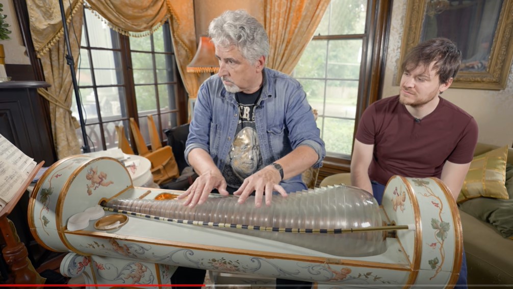 Glass Armonica being played by an older white man while a younger white man looks on