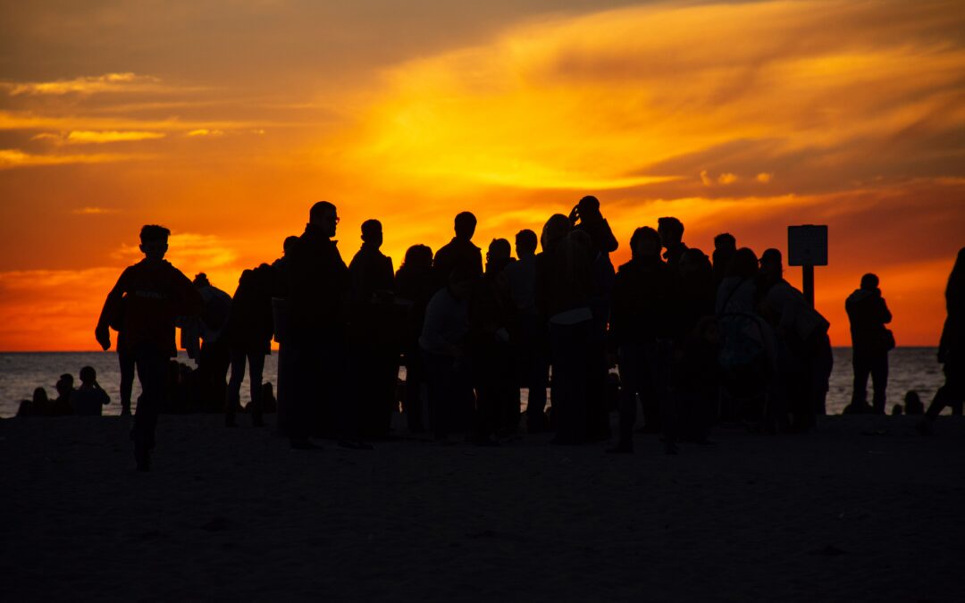 gathering of people silhouetted against a sunset